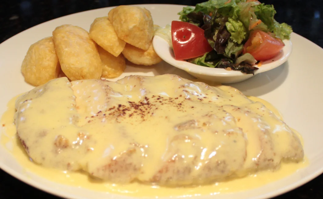 Filete de carne en salsa de queso con patacones y ensalada fresca en Ali's Parrilladas & Pizzería, restaurante de carnes en Quito.