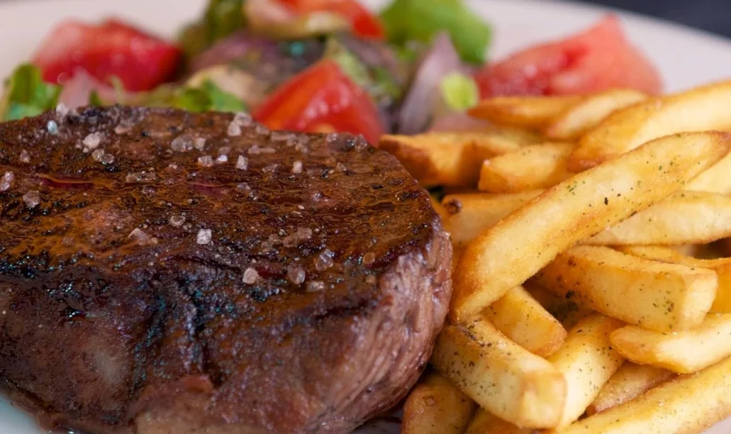 Lomo a la parrilla con papas fritas y ensalada fresca en Ananké Guápulo, restaurante con vista al valle de Cumbayá en Quito.
