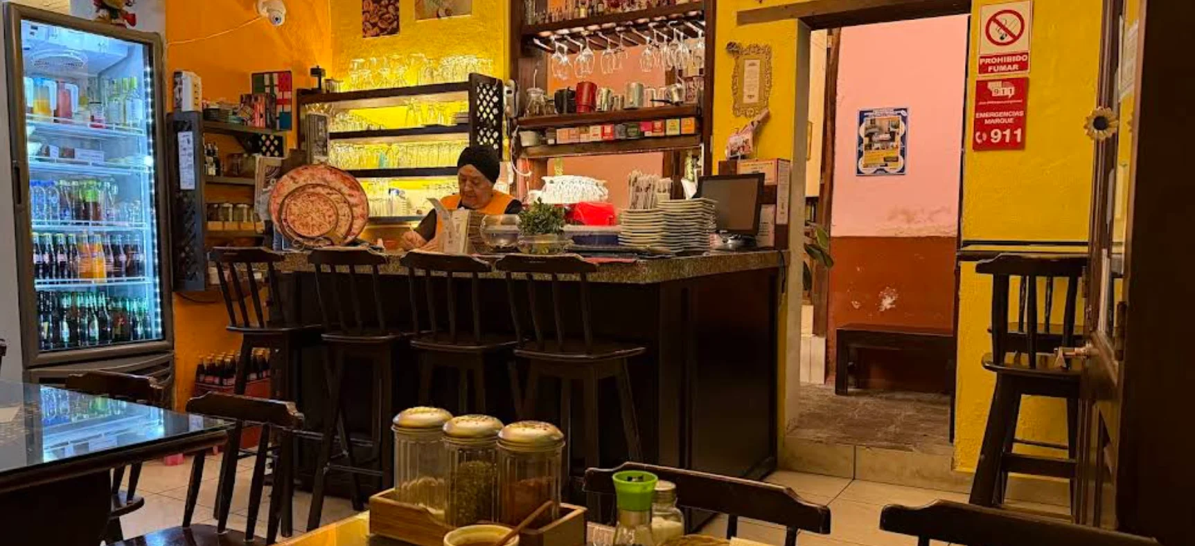 Interior rústico del restaurante Café San Blas con barra de madera y paredes amarillas.