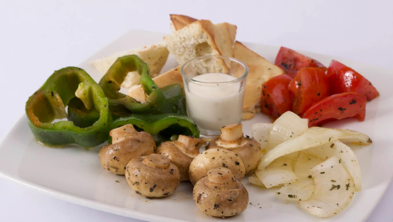 Plato de aperitivo con champiñones, pimientos, cebolla asada, tomates y pan pita servido con salsa en Café San Blas Quito.