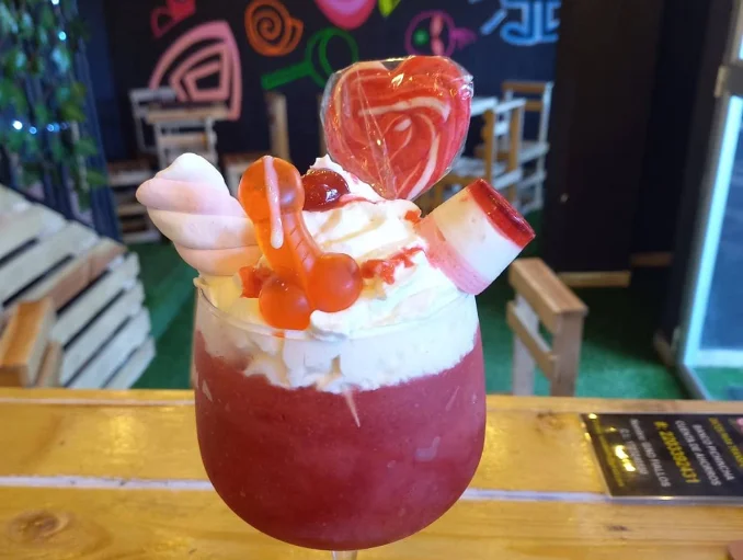 Cóctel granizado frutal en Candy By Salsa Sur Quitumbe 2, decorado con crema batida, gomitas de formas divertidas, malvaviscos y una paleta de corazón.