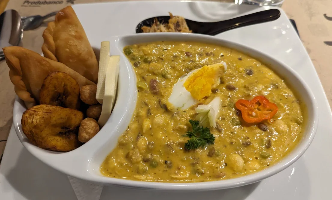 Fanesca ecuatoriana con huevo duro, ají y perejil, acompañada de empanadas, maduro frito y queso fresco en Cinco Sentidos, restaurante de fusión en Quito.