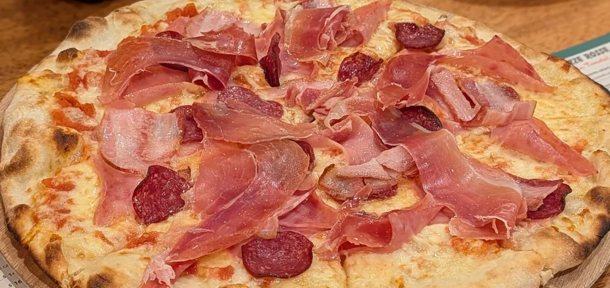 Pizza artesanal con prosciutto, salami y queso al horno de leña en Cosa Nostra Trattoria & Pizzería, Quito.