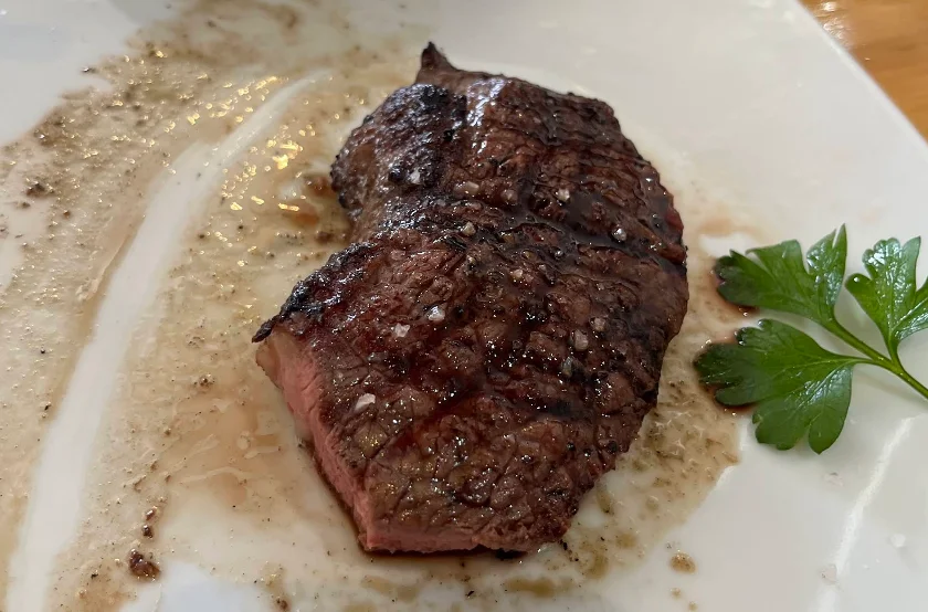 Bife a la parrilla cortado con perejil fresco, plato de El Chacal Parrilla en Quito.