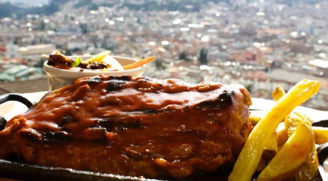 Costillas BBQ con papas fritas y vista panorámica de Quito en El Escondite de Cantúña