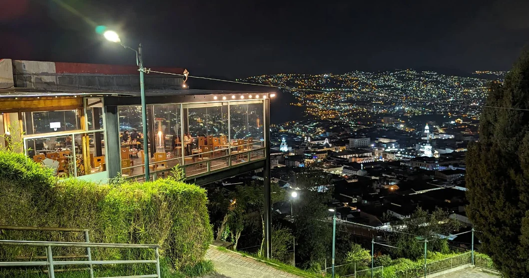 Restaurante mirador El Ventanal de noche en San Juan, Quito, con vista panorámica iluminada del Centro Histórico y la Basílica del Voto Nacional.