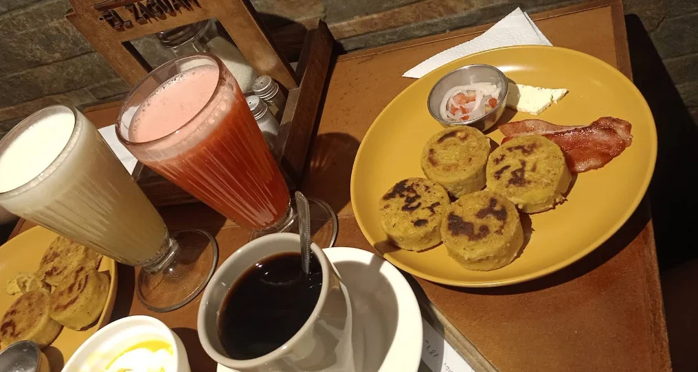 Desayuno ecuatoriano en El Zaguán Cafetería del Centro Histórico de Quito, con llapingachos, tocino, café negro y jugos naturales de frutas.