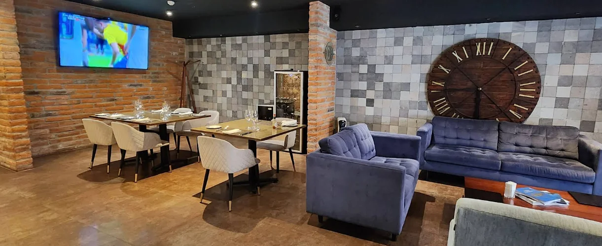 Interior del Restaurante Enciende Tus Sentidos con sofás azules, paredes de ladrillo visto y decoración industrial moderna.