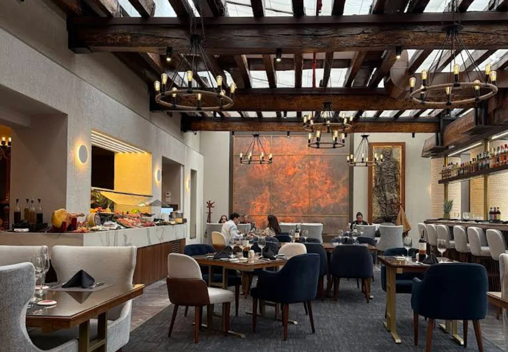 Interior elegante del restaurante Fogo de Chão con techos de vigas y buffet de ensaladas.