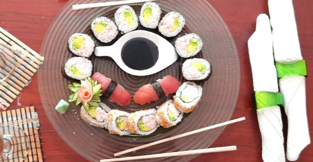 Plato circular con variedad de sushi en el restaurante Katana Sushi en Quito, incluyendo maki rolls de aguacate, uramakis y niguiris de atún alrededor de un cuenco con salsa de soya.