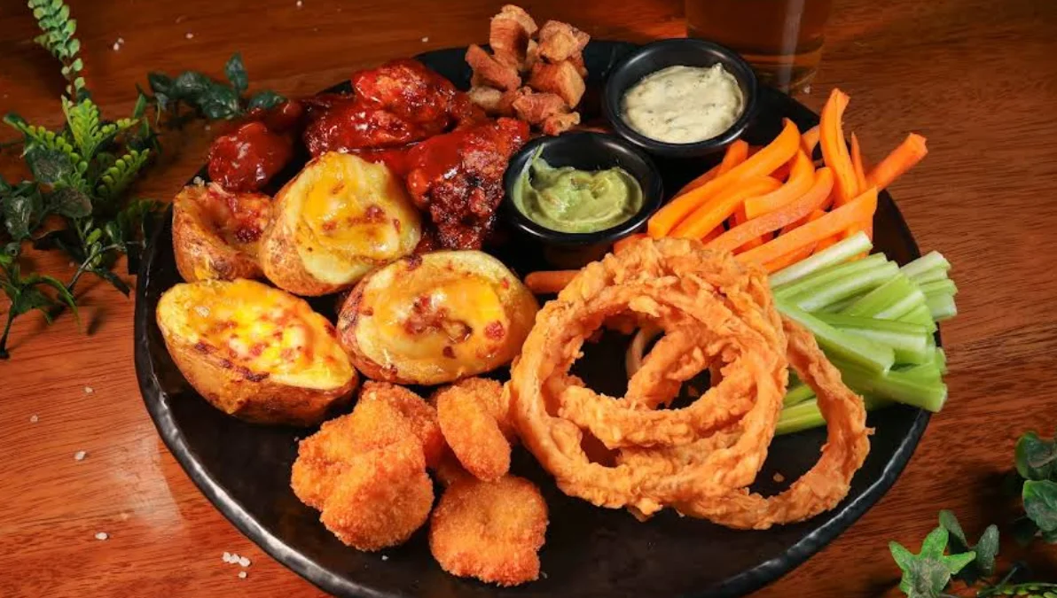 Tabla de piqueo con alitas, papas rellenas, aros de cebolla y vegetales en Katari Cumbayá, pub restaurante en Cumbayá, Quito.