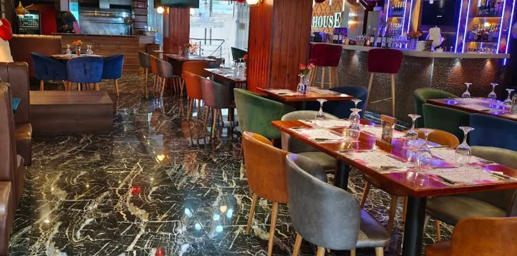 Interior elegante del restaurante Kingdom House en el Sur de Quito, con pisos de mármol negro, mobiliario aterciopelado de colores y una barra de coctelería iluminada al fondo.