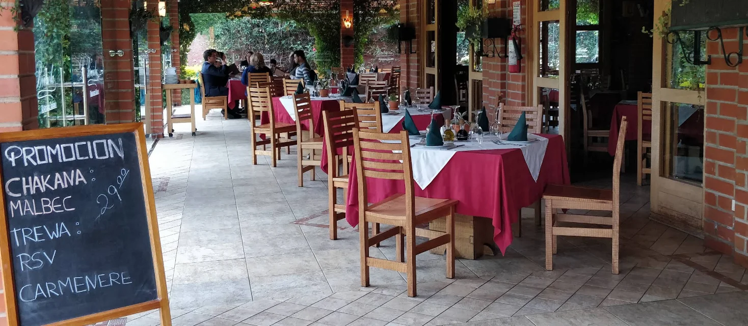 Vista interior del acogedor restaurante La Briciola en Cumbayá, con techos de madera y múltiples luces colgantes.