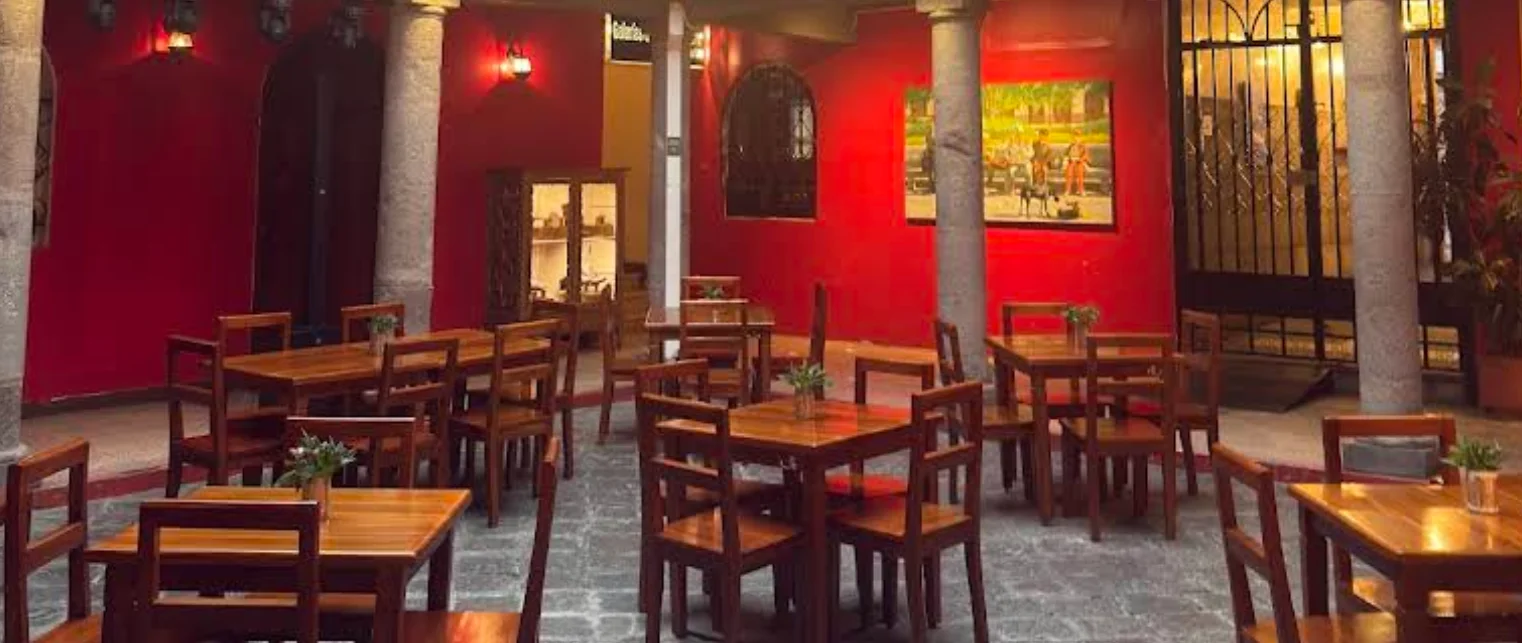 Comedor del restaurante La Caponata en el Centro Histórico de Quito, decoración colonial con detalles en rojo.