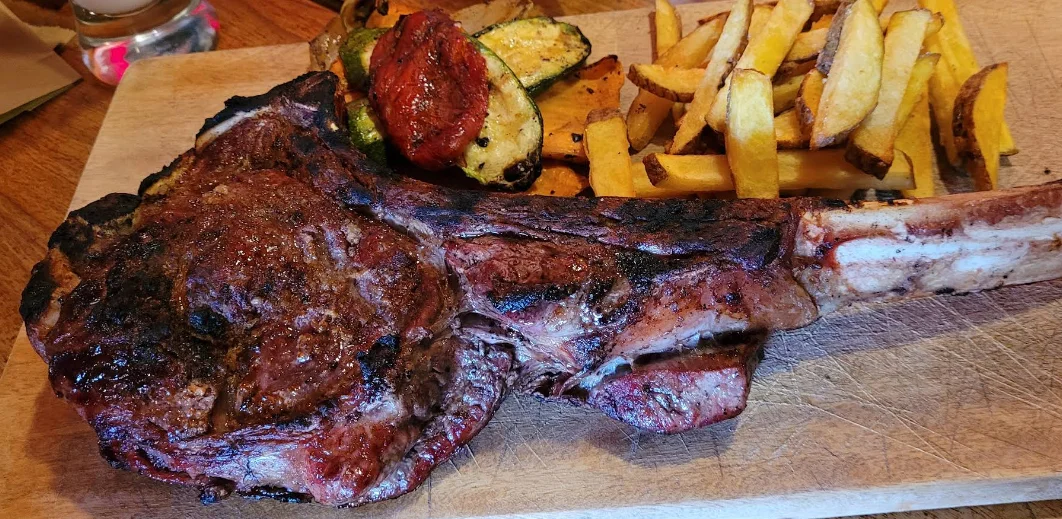 Chuletón a la parrilla con vegetales asados y papas fritas en La Carnicería, restaurante de cortes en La Mariscal, Quito.