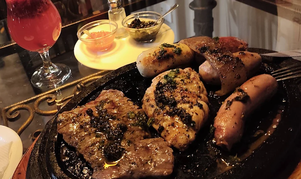Parrillada mixta con carne, pollo y chorizo bañados en chimichurri, plato de La Chimenea - Parrillas & Restaurant en Quito.