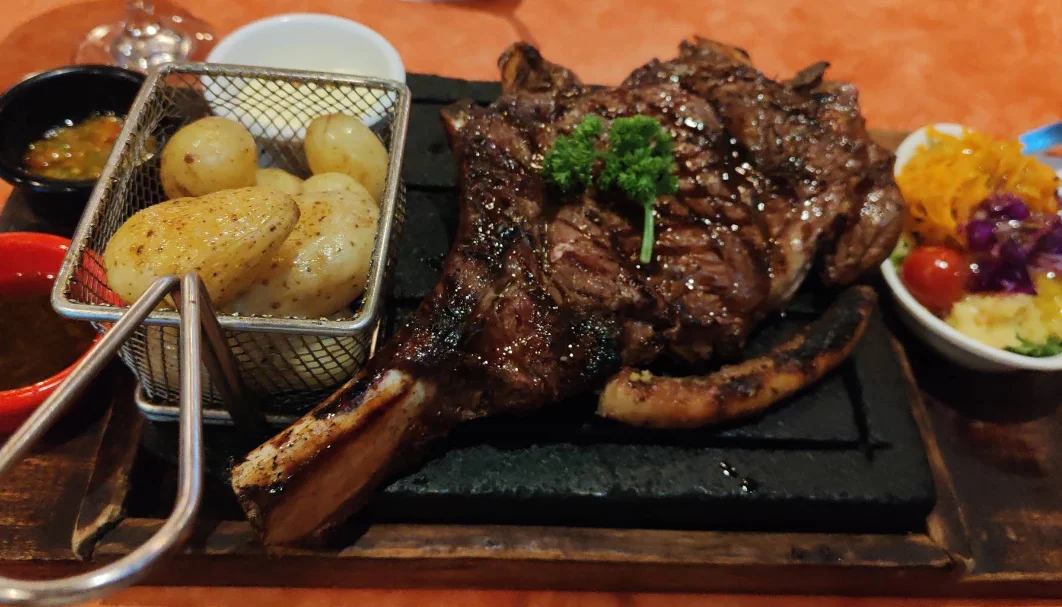 Chuletón a la parrilla sobre piedra volcánica con papas fritas y ensalada, plato de La Concha de la Lora en Quito.