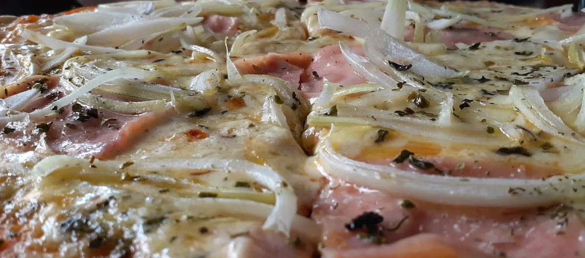 Pizza artesanal de jamón con queso mozzarella fundido, cebolla blanca y orégano en La Gambugia, pizzería italiana en Tumbaco.