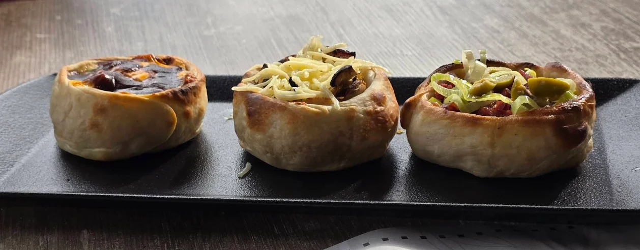 Trío de empanadas argentinas horneadas con distintos rellenos en La Milanga Porteña, Cumbayá.