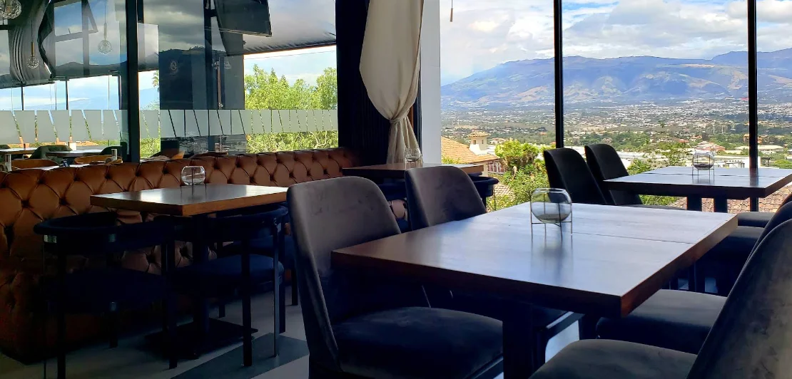 Salón interior de La Parrilla de Homero Cumbayá con vista panorámica al valle.