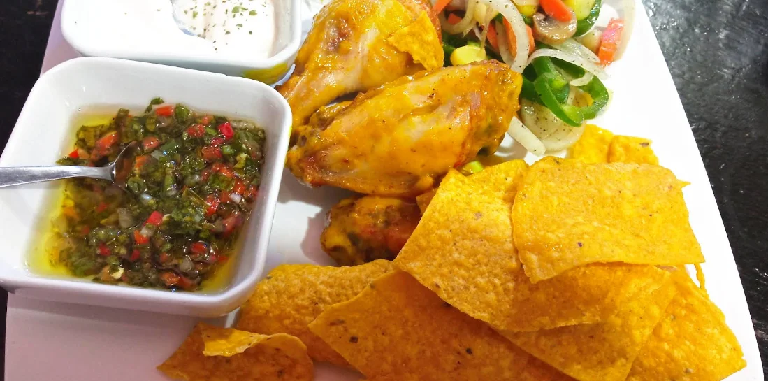 Alitas de pollo con chimichurri, crema, nachos y ensalada en La Tabernita Resto Bar, Quito.