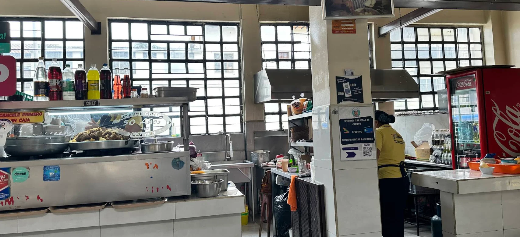 Puesto de comida tradicional de Las Corvinas de Don Jimmy en el Mercado Central de Quito, con bandejas de pescado frito y letrero de '50 años de tradición'.