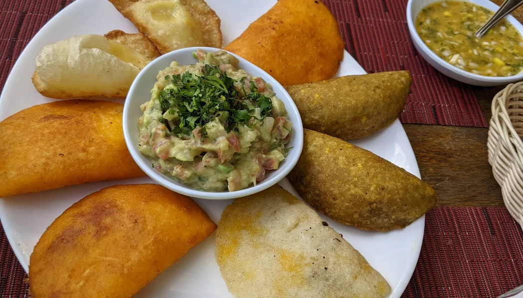 Tabla de empanadas ecuatorianas variadas en Leña Quiteña-La Ronda: empanadas de viento, morocho y queso con guacamole casero y ají de tomate, típicas de la cocina quiteña.