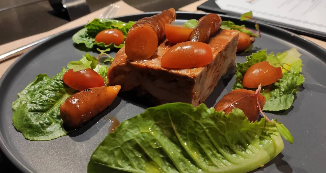 Terrina de cerdo con tomates cherry y hojas verdes en Los Troncos Fuegos Ancestrales, restaurante de parrilla en Quito.