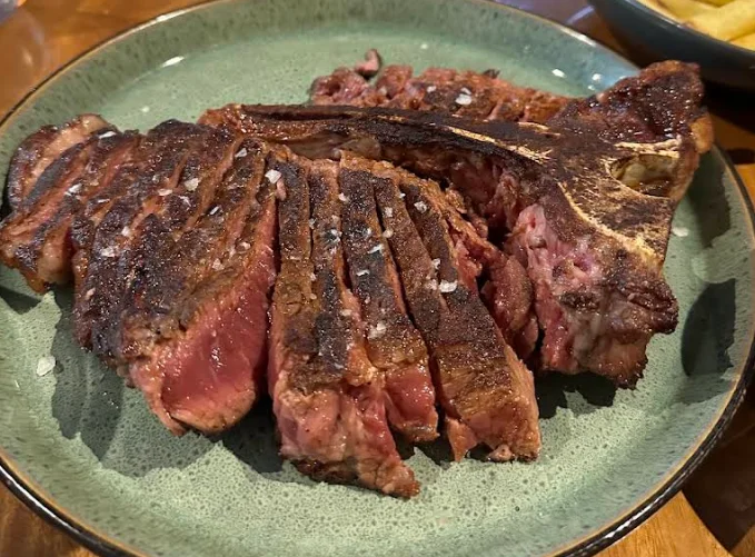 T-bone a la parrilla cortado en tajadas con sal gruesa, plato de Los Troncos Fuegos Ancestrales en Quito.