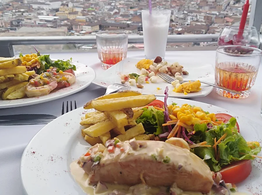 Pechuga de pollo en salsa cremosa con papas fritas y ensalada colorida con vista panorámica al Centro Histórico de Quito en el restaurante Luna Quiteña.