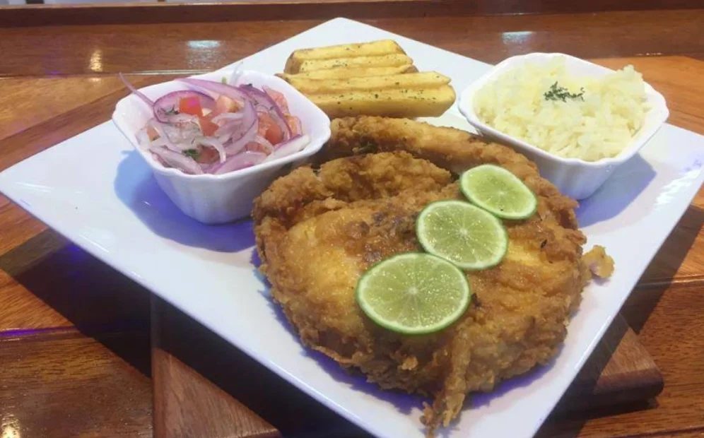 Corvina frita con papas fritas, arroz y curtido de cebolla en el restaurante Mirador Vistasur en Quito.