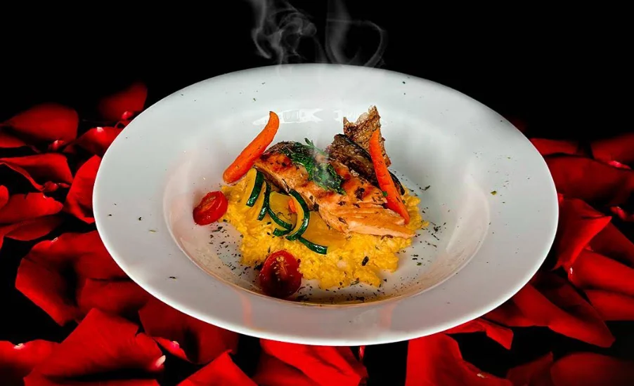 Plato de salmón con risotto y pétalos de rosa en Romeo & Julieta Quito.