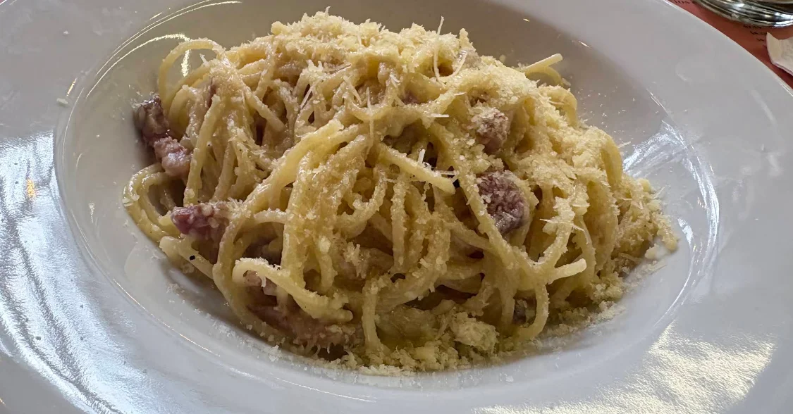 Alt: Spaghetti a la carbonara con parmesano en Romolo e Remo Quito.