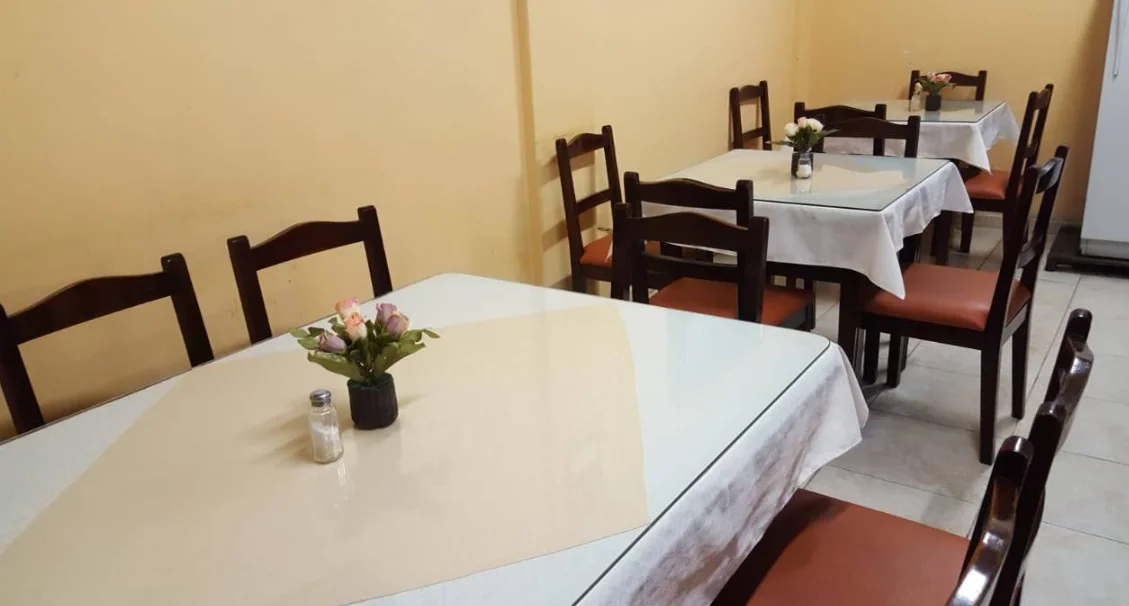 Mesas y sillas de madera en el comedor del Salón Panchito con paredes amarillas.