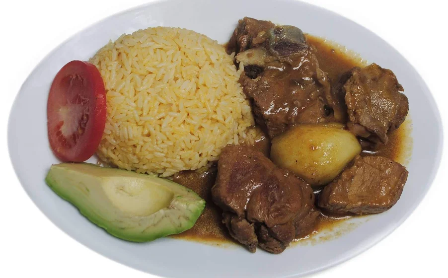Plato típico ecuatoriano de carne en salsa con arroz amarillo, papa, aguacate y tomate en restaurante San Francisco, Quito.