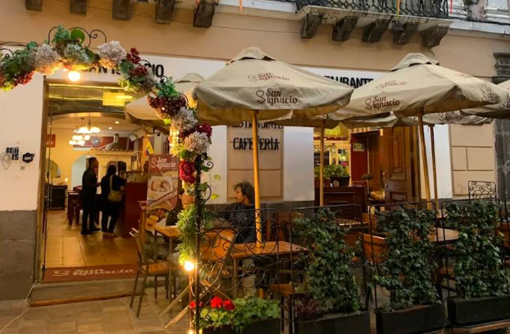 Terraza exterior del Restaurante San Ignacio en el Centro Histórico de Quito con sombrillas y decoración floral.