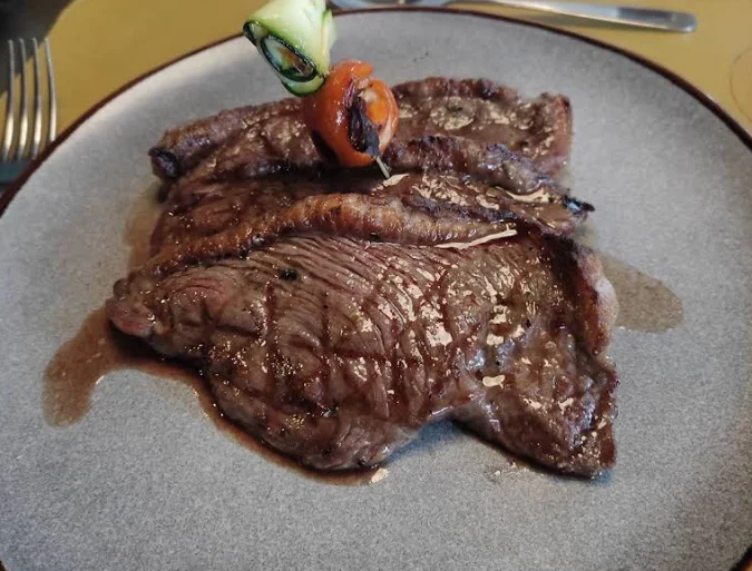 Corte de res a la parrilla en su jugo, decorado con brocheta de vegetales, plato de Sur - Parrilla Gourmet en Quito.