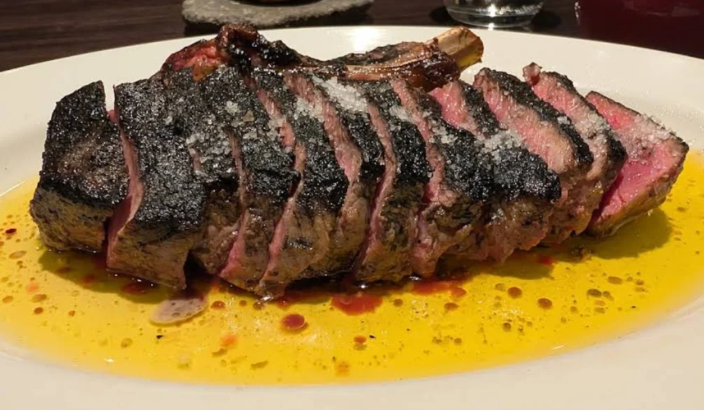 Chuletón de res cortado en tajadas con sal gruesa y jugo de cocción, plato de Tributo en Quito.