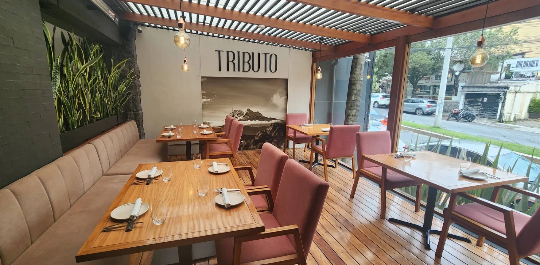 Interior elegante y moderno del Restaurante Tributo en Quito, destacando las mesas de madera, iluminación cálida y exhibición de cortes de carne madurada (dry-aged)