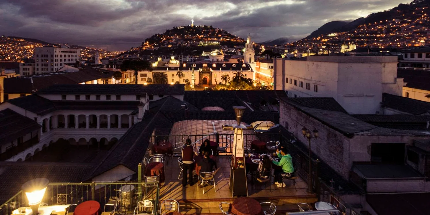 Terraza nocturna del restaurante Vista Hermosa con vista panorámica al Centro Histórico de Quito y el Panecillo iluminado.