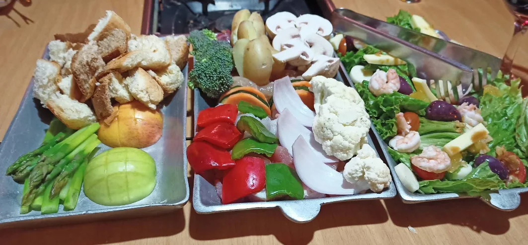 Tabla de fondue con vegetales, pan y ensalada de mariscos, experiencia gastronómica de Voilà Bistro Jardín en Quito.