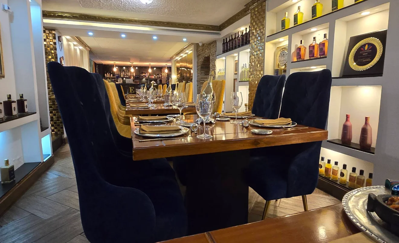 Salón principal del restaurante Zero Lab en Quito con sillas de terciopelo azul, mesas de madera pulida y estanterías con botellas decorativas.