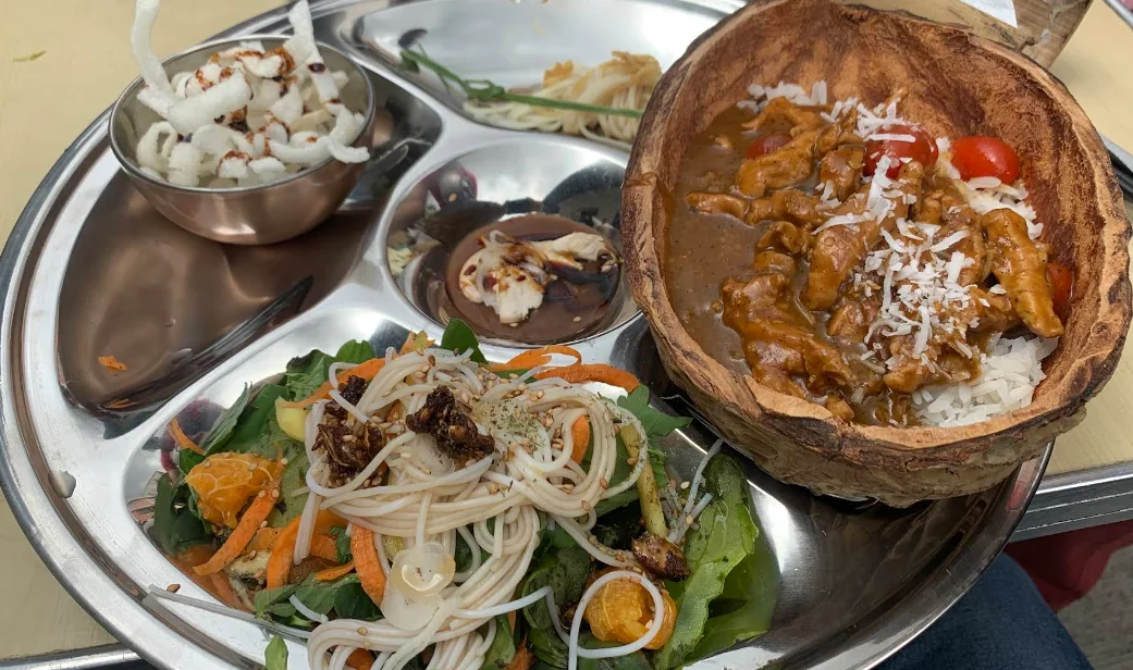 Curry de pollo con coco en bol de coco y ensalada de fideos en Zingaro Quito.